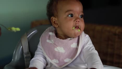 una niña siendo alimentada mientras está en una silla alta.