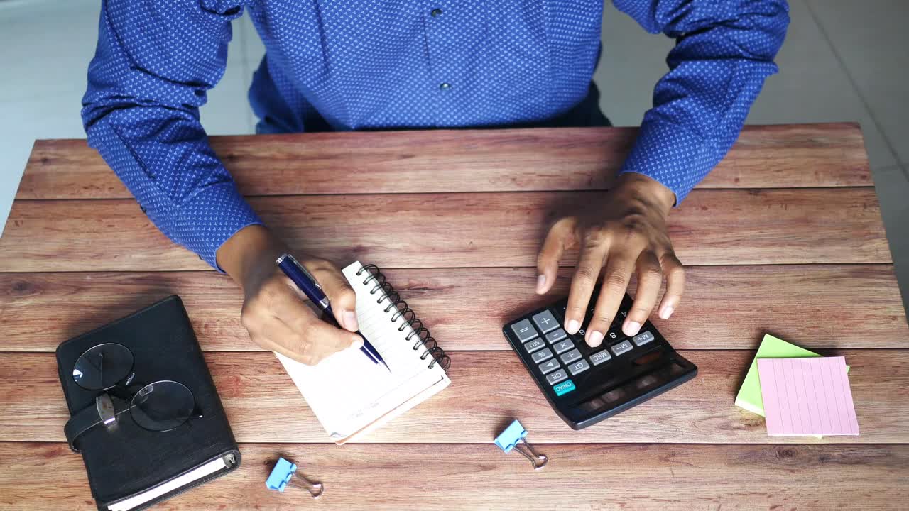 persona que hace cálculos en un escritorio de madera