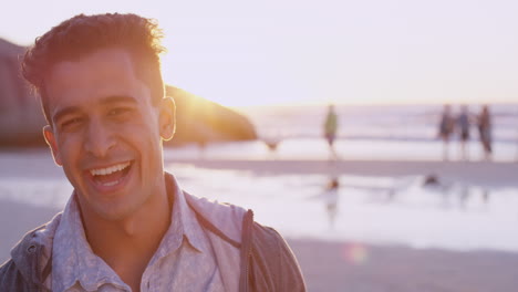 portrait of attractive man smiling on beach at sunset in slow motion