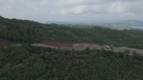 Aerial-view-of-Road-and-forest-in-Montserrat-mountains-with-pine-trees-and-fog