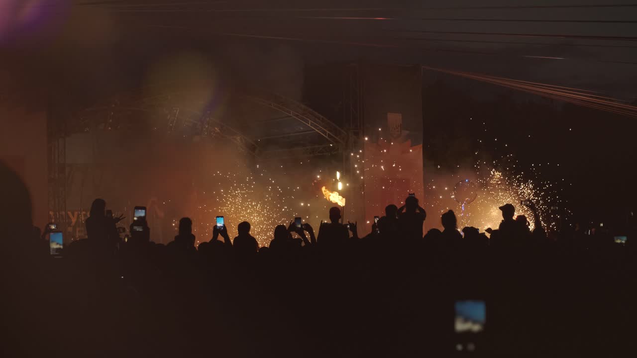 많은 사람들이 휴대 전화로 불꽃놀이와 불꽃 쇼를 촬영하고 있습니다. 활기찬 불꽃과 다채로운 불꽃놀이는 밤 하늘을 밝히고, 전기적인 분위기를 만니다.