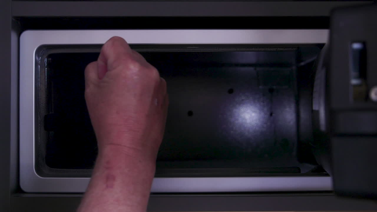 A hand, seemingly frustrated and angry, finds that the safe is empty and the possessions are gone. Opening a safe with a digital keypad.