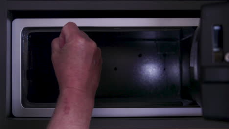 a hand, seemingly frustrated and angry, finds that the safe is empty and the possessions are gone. opening a safe with a digital keypad.
