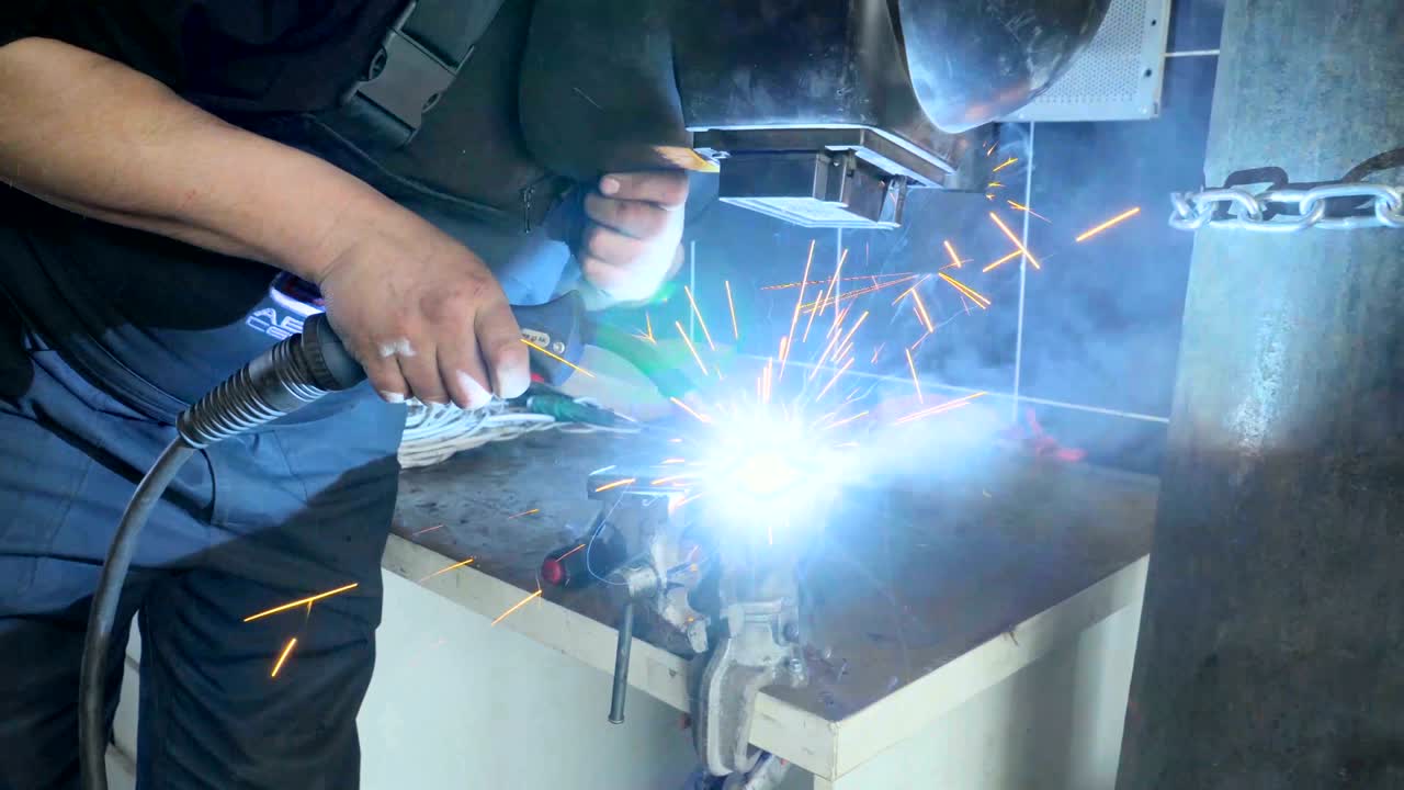 Closeup employee in a mask doing the welding in a workshop