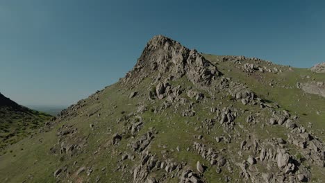 aerial shot flying towards an old eroded mountain peak on a sunny clear day