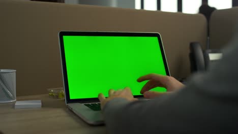 hombre de negocios escribiendo computadora portátil pantalla verde en la oficina. hombre usando computadora portátil