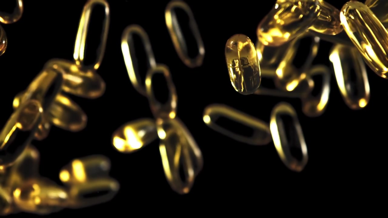 Capsule softgel di Omega-3 dorate che cadono al rallentatore su sfondo nero