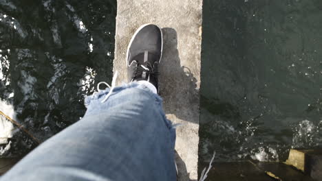POV-video:-The-feet-of-a-young-male-traveler-are-walking-along-a-narrow-bridge-over-a-river