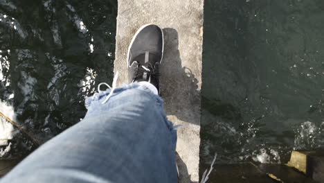 pov video: the feet of a young male traveler are walking along a narrow bridge over a river