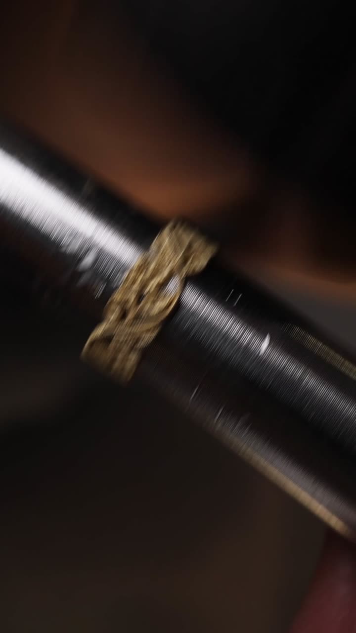 Artesano dando forma a un anillo de oro ornamentado con martillo sobre un mandril