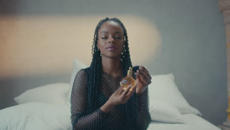 Front-view-of-a-smiling-dark-skinned-girl-applying-perfume-on-her-neck