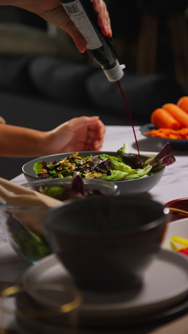 video vertical de cerca de una mujer en casa en la cocina preparando una comida saludable vegetariana o vegana vertiendo el aderezo en un cuenco de hojas de ensalada
