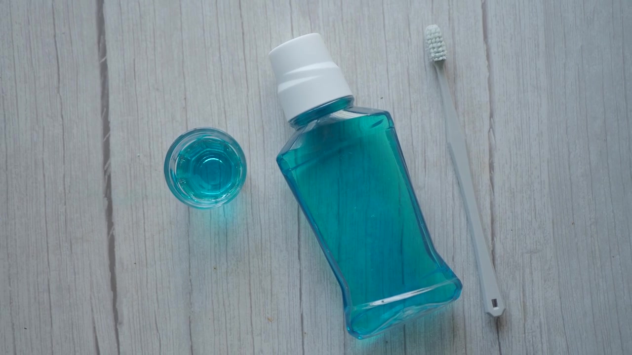 Botella de enjuague bucal y cepillo de dientes sobre una superficie de madera