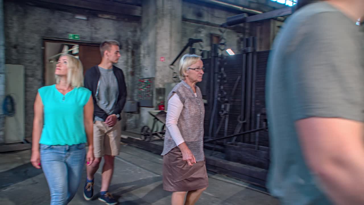 Orbit shot of a tour guide showing the Ironmaking museum to a group of tourists