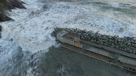 enormes olas marinas espumosas rompiendo en el muelle del rompedor de olas del puerto en génova