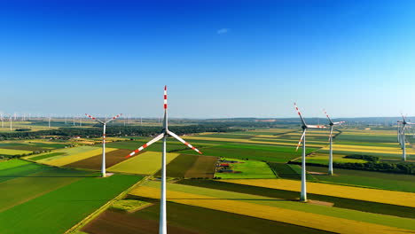 amazing summer field with bright colored patches. aerial perspective on the wind turbines rotating in the wind.