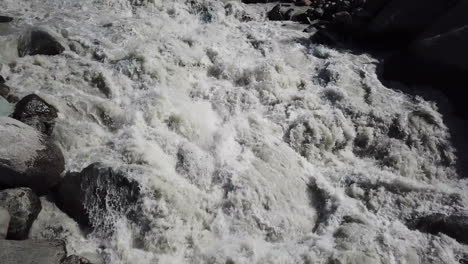 Drone-top-view-of-a-muddy-steep-mountain-turrent,-Swiss-alps-water-from-the-glacier