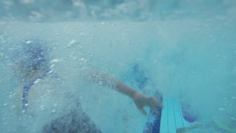 fotografía submarina de niños saltando a la piscina cubierta desde el borde