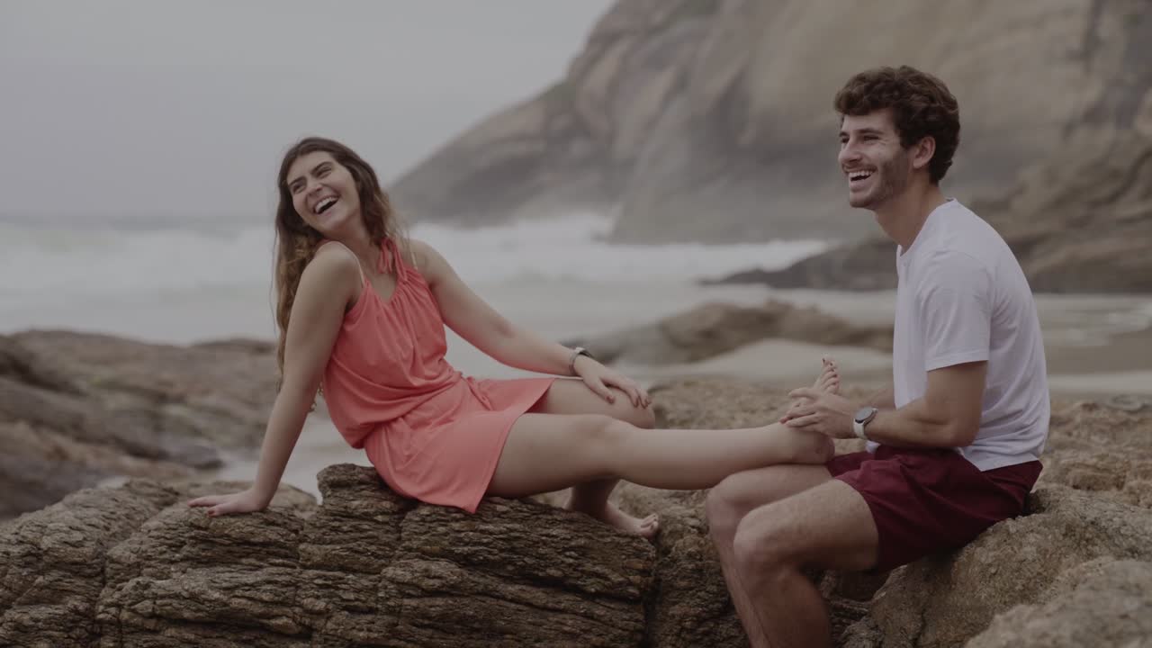 A couple enjoys a relaxing foot massage on a rocky beach