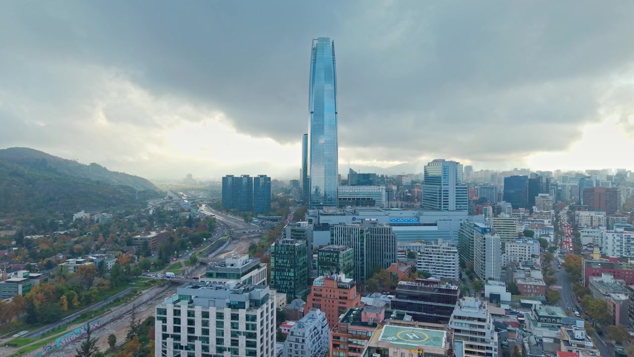 Vista a volo d'uccello del quartiere Providencia, con la sua grande e moderna torre Costanera e la città avvolta in una fitta nuvola, Santiago, Cile.
