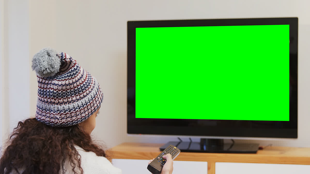 Smiling woman in warm clothing watching television 4K 4k
