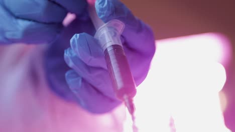 hands of doctor wearing gloves carefully absorb the red liquid into syringe for testing coronavirus infection on patients