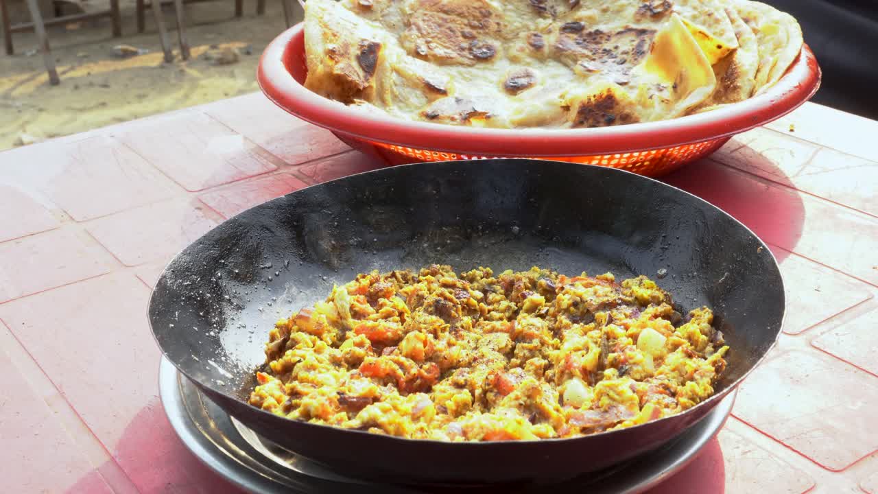 At a charming local dhaba, people relish a delightful breakfast featuring warm, crispy parathas served alongside a flavorful omelet.