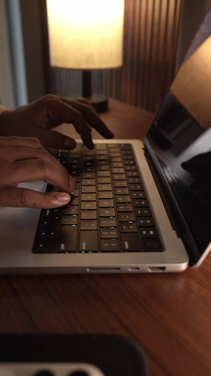 Hands Typing on Laptop Keyboard in Warm Cozy Lighted Room.