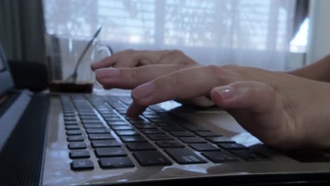 side view of female developer's hands typing code on a laptop keyboard