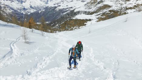 couple of snowshoers walking snowy trail, winter sports, italian alps. aerial drone low altitude