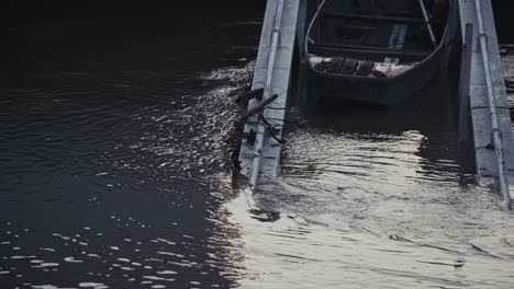 damaged dock structure partially submerged in water, debris entangled, near a boat