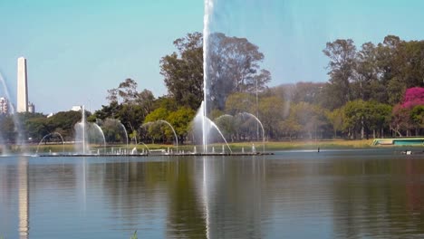 dancing-water-fountains-on-the-lake-of-Ibirapuera-park,-and-obelisk-on-the-back