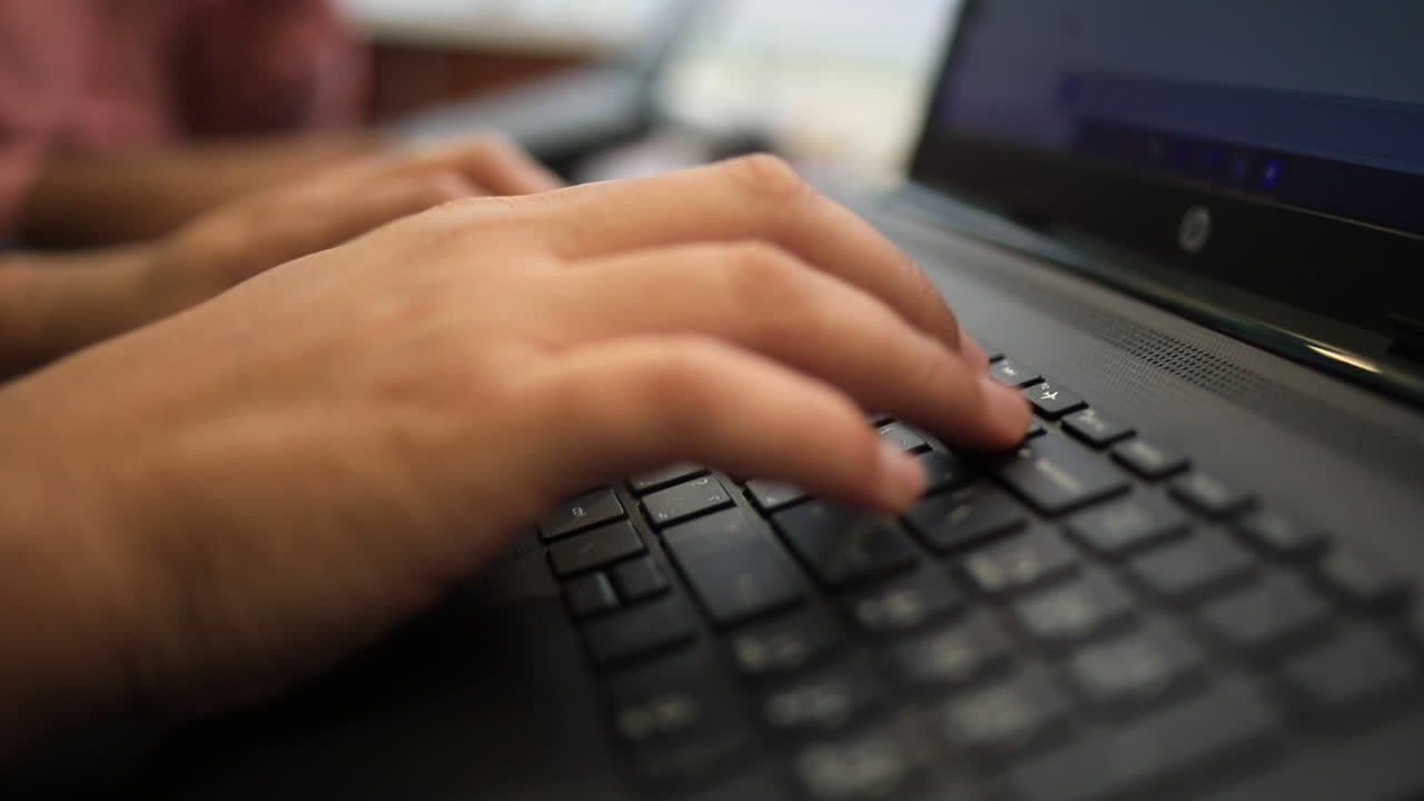 A man's hand typing on a laptop keyboard from the side - close up