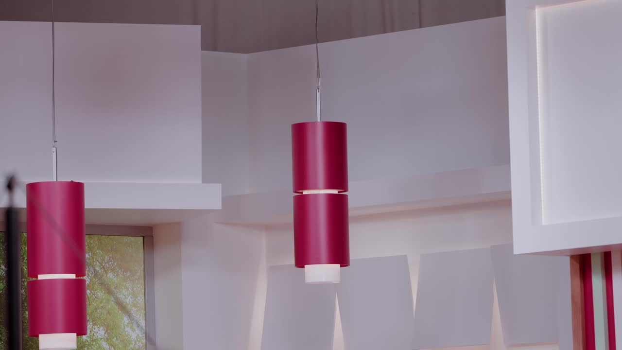 Närbild på röda cylindriska taklampor i ett ljust modernt rum