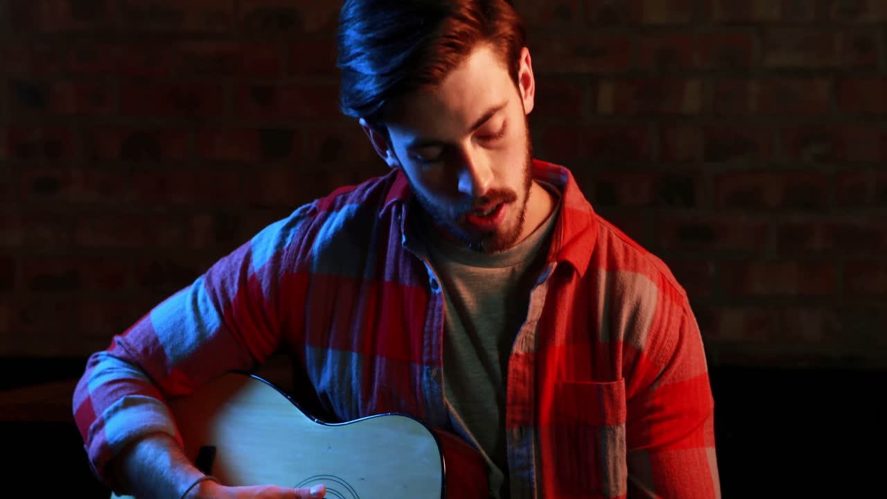 guapo músico cantando una canción mientras toca la guitarra