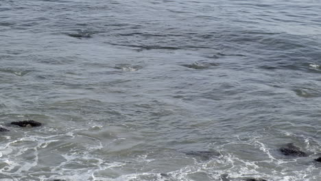 Serene-nostalgia,-ocean-water-waves-forming-and-hitting-the-rock-shoreline-at-Big-Rock-Malibu-beach