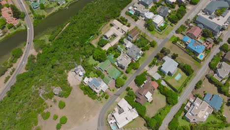 Birds-eye-view-of-group-of-luxury-residences-on-hill-above-valley-with-river.-Steep-slope-overgrown-with-trees-and-shrubs.-Plettenberg-Bay,-South-Africa