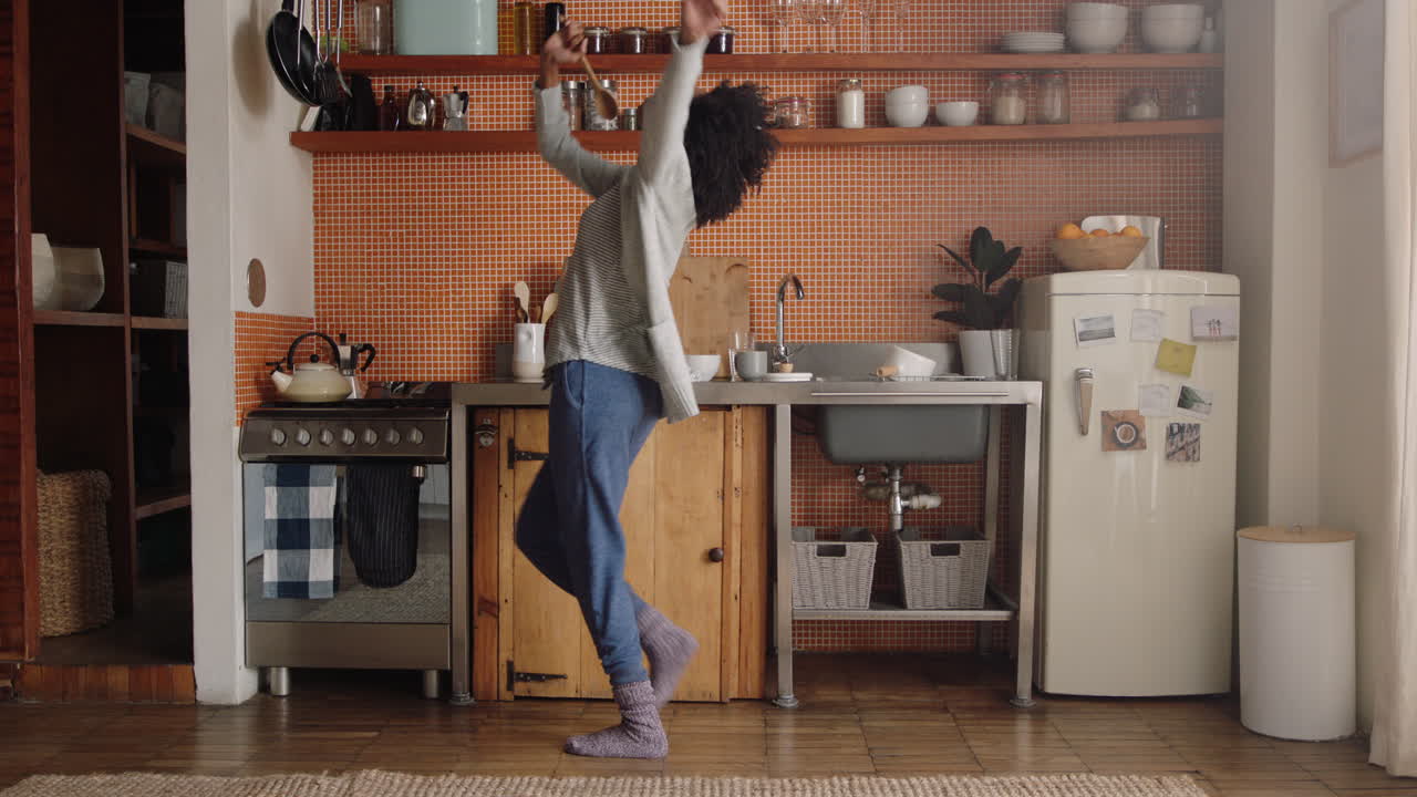 happy woman dancing in kitchen celebrating successful lifestyle enjoying cheerful victory dance celebration