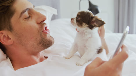 young man lying on bed stroking his puppy while using mobile phone 4k 4k