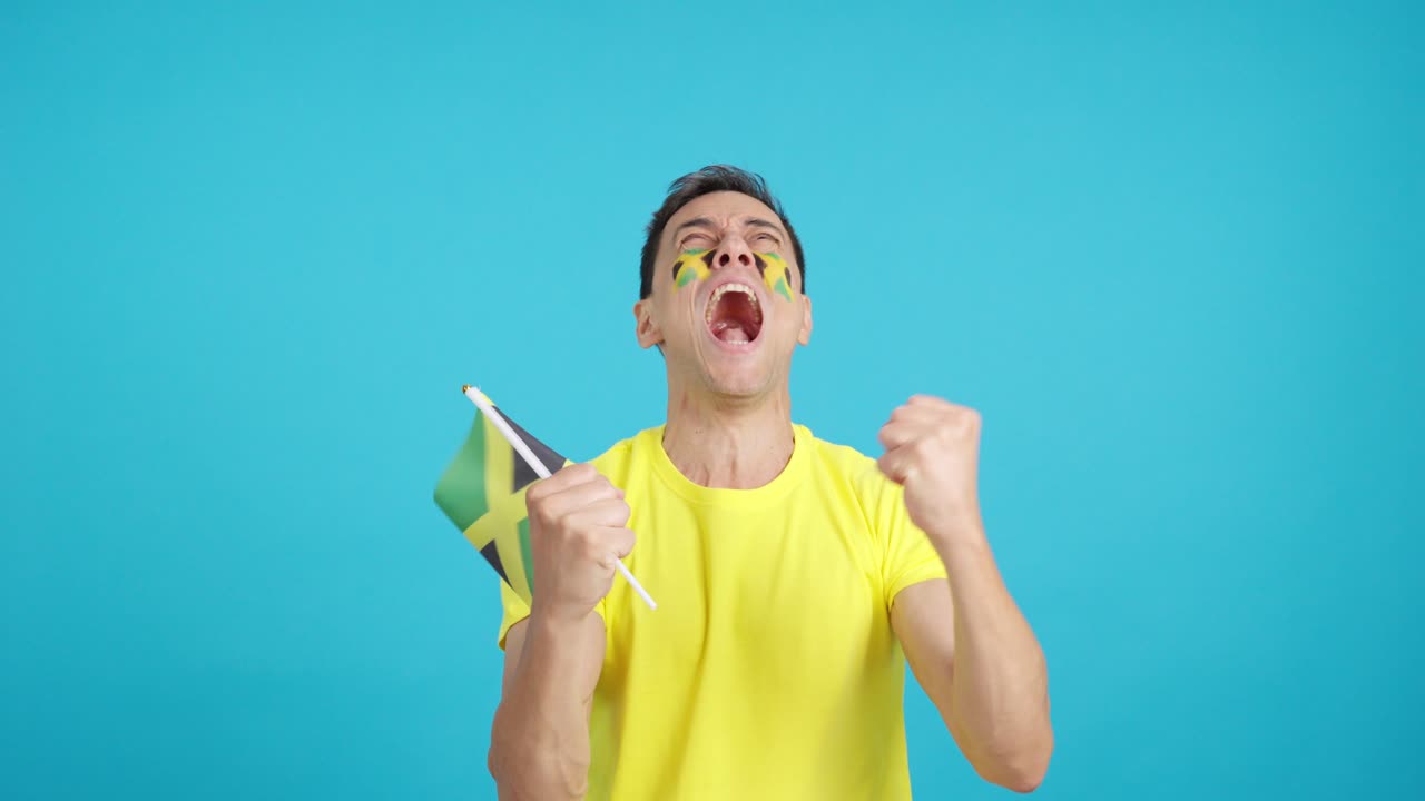 Man cheering for Jamaica screaming and waving a national flag