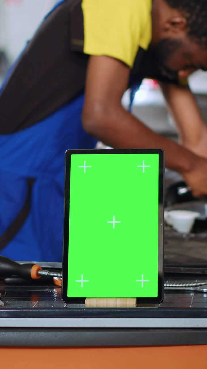 Video verticale Meccanico auto accanto a tablet con green screen