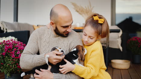 father and daughter are sitting on the doorstep of their house, playing with puppies