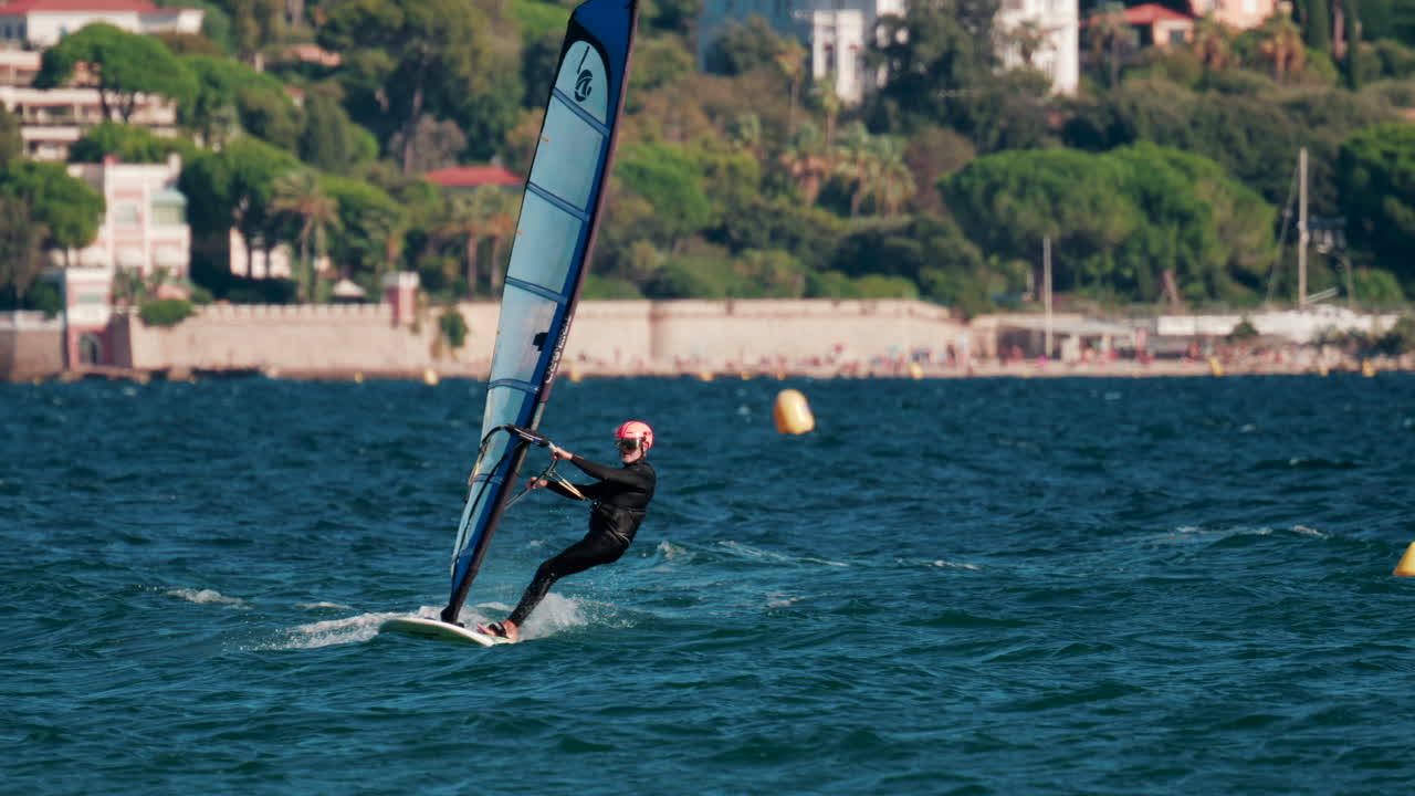 Cannes, France - October 5, 2025: Athlete windsurfing on turquoise sea on a sunny day