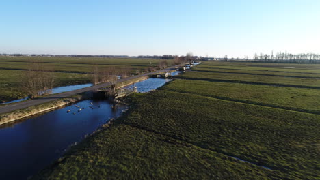 stolwijk in krimpenerwaard, netherlands - drone flying low above vast green field with frozen ditches and wooden fences