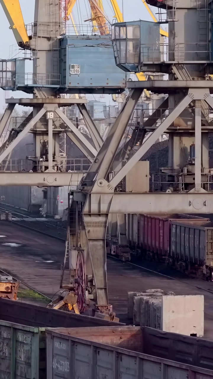 Industrial Port Cranes Loading Coal Wagons, Giant Gantry Structures Transferring Bulk Coal Into Long Line
