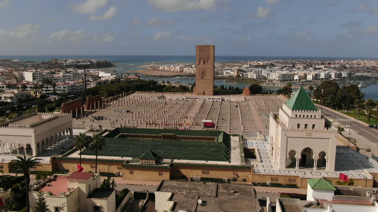 Betagende HD-luftpanorama af Hassan Tower-komplekset og V Mausoleet i Rabat, Marokko. Fanger den historiske minaret, marmorsøjlerne og den kongelige grav mod Bou Regreg-floden og Atlanterhavet.