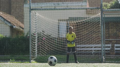 african american soccer kid in red scoring in a sunny day