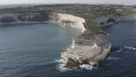 A drone circles the dramatic limestone cliffs of Ras il-Fenek, revealing sheer rock faces and the endless blue sea along Malta’s rugged coast