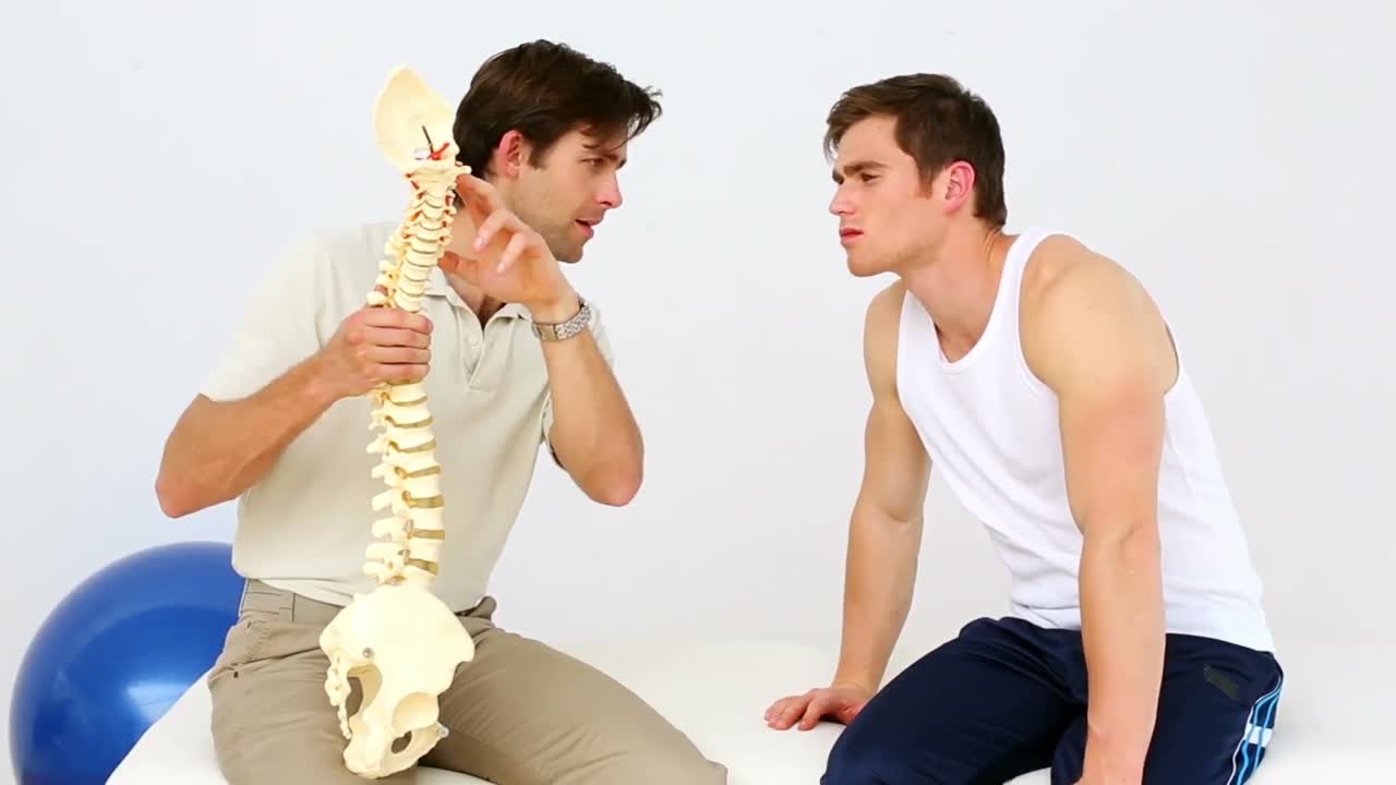 물리치료사가 환자에게 척추 모델을 보여주고 있습니다.