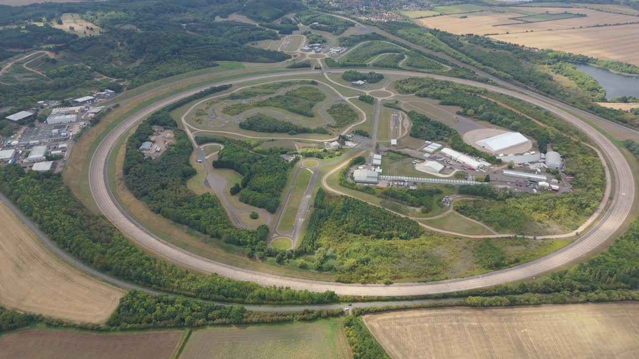 Drone aerial footage of Bedford vehicle testing track UK showing proving grounds, research and innovation on cars, rural landscape and rolling countryside